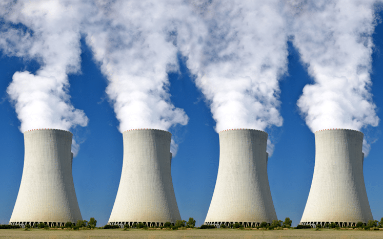 Cooling towers emitting steam against a clear blue sky, representing energy-intensive industries and their environmental impact.