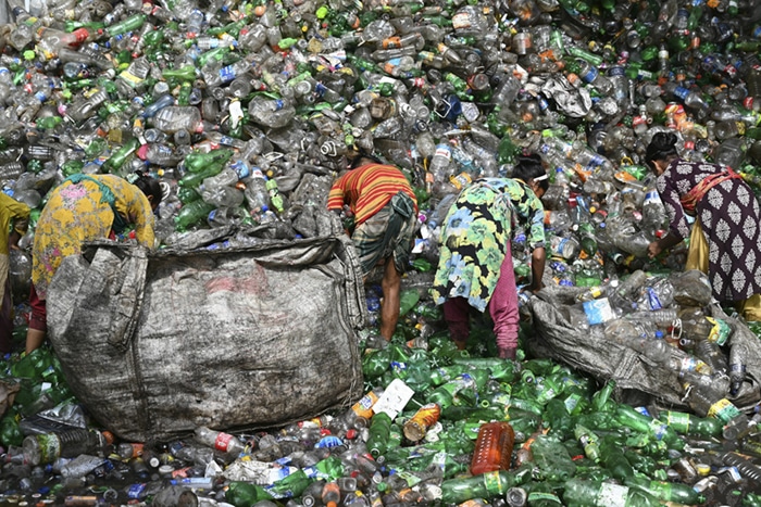Women sorting through a large pile of plastic waste in a recycling effort, highlighting the global issue of plastic pollution and the need for sustainable practices.