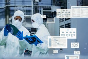 Two cleanroom technicians inspect a silicon wafer and a tablet as digital data panels overlay the image.